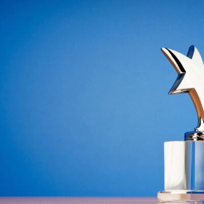 A silver star trophy on a table against a blue background.