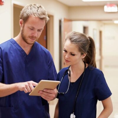 Two nurses reviewing patient data on tablet.