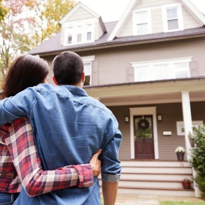 A couple standing in front of a house.