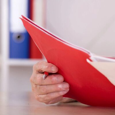 A man is holding a red folder.