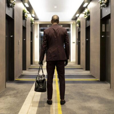 Man in suit with bag in hotel hallway.