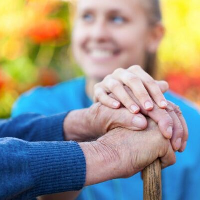 An elderly woman is holding an elderly woman's hand.