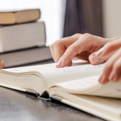 Two people reading a book on a table.