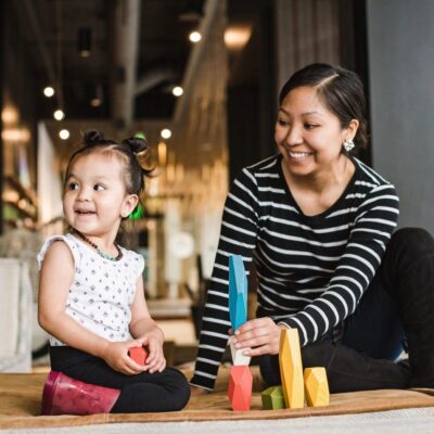 A mother and daughter playing with blocks in a living room.