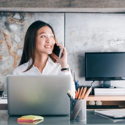 A woman sitting at her desk talking on the phone.