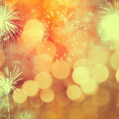 Fireworks on a golden background with bokeh lights.