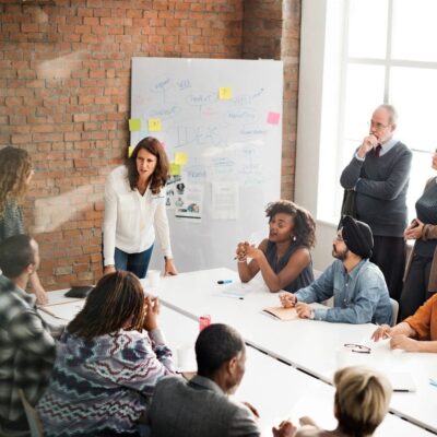 Woman presenting to a diverse group in a modern office meeting.