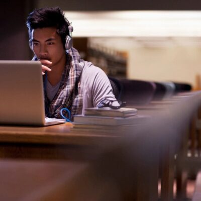 Student studying on laptop in library.