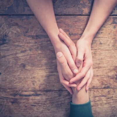 Two people holding hands on a wooden table.