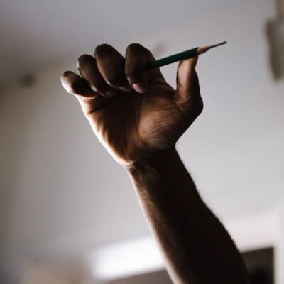 A hand holding a pencil up in the air.