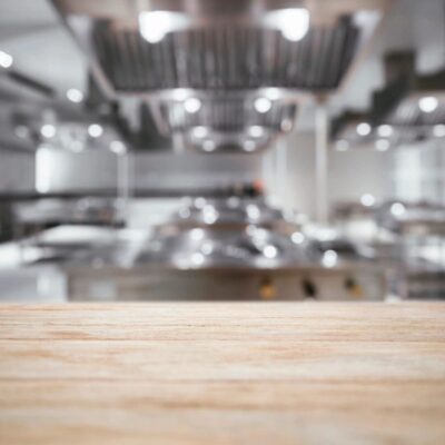 Wooden table, blurred restaurant kitchen background.
