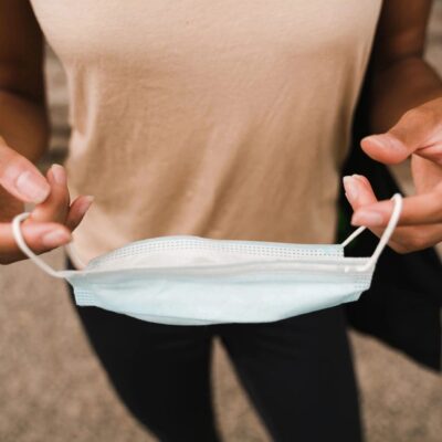 A woman holding a surgical mask in her hands.
