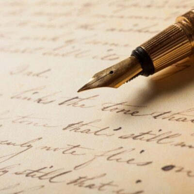 A fountain pen sits on top of an old letter.