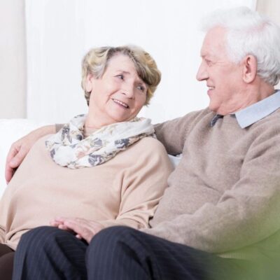Elderly couple sharing a warm moment on the couch.