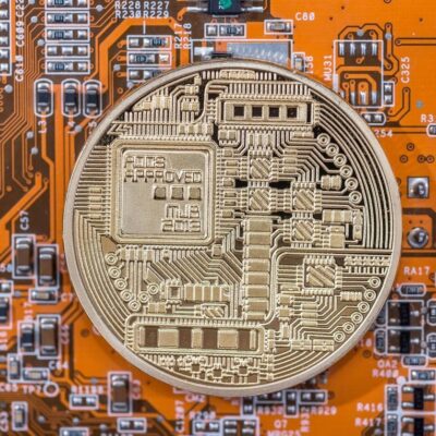 Cryptocurrency coin on an orange circuit board.