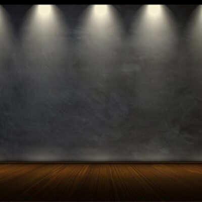 Empty stage with spotlight beams on a dark textured backdrop.