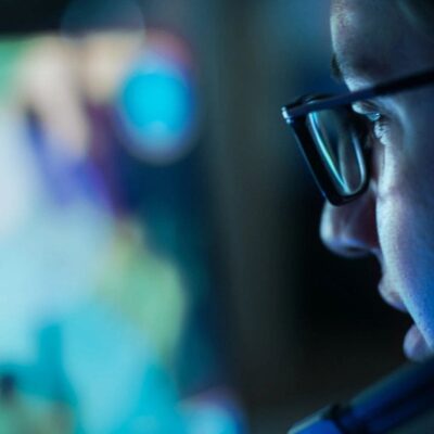 Gamer wearing glasses plays video game.