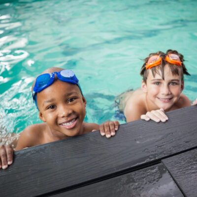 Two boys in swimming goggles smiling at the camera.