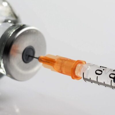 Syringe drawing medication from vial.