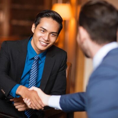 Asian businessman shaking hands with a man in a suit.
