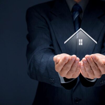Businessman holding a house in his hands.