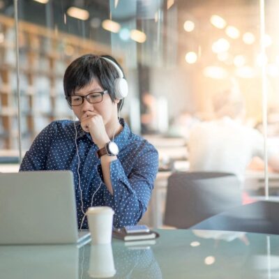 Woman working thoughtfully on her laptop in a cozy café.