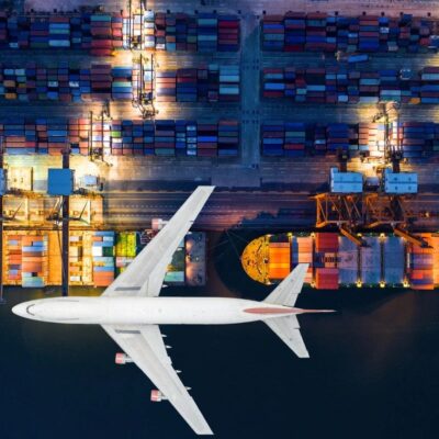 An airplane is flying over cargo containers at night.