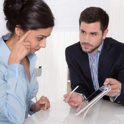 A man explaining something on a tablet to a woman in an office setting.