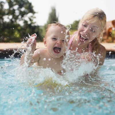 Two children playing in a pool with water splashing around them.