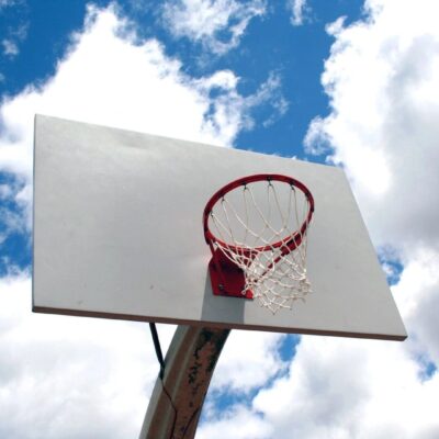 A basketball hoop and backboard under a partly cloudy sky.