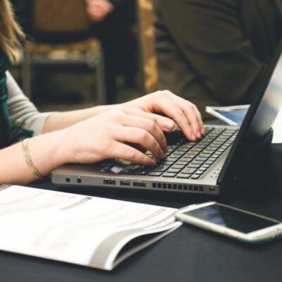 A woman typing on a laptop at a conference.