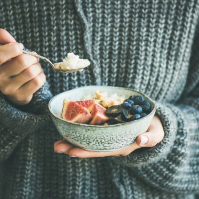 A person holding a bowl of yogurt and berries.