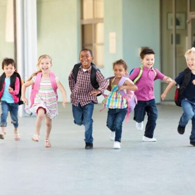Happy kids race to school with backpacks.