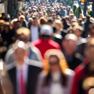A blurry image of a crowd of people walking down a street.