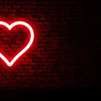 A red heart neon sign on a brick wall.
