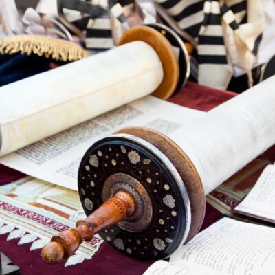 A group of people are sitting around a table with a torah.