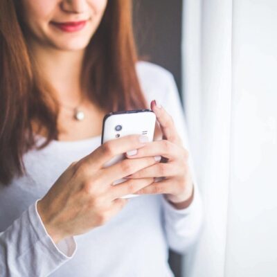 Woman using smartphone near window.