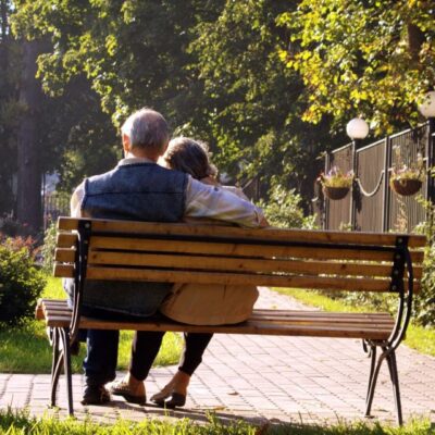 A couple sitting on a bench in a park.