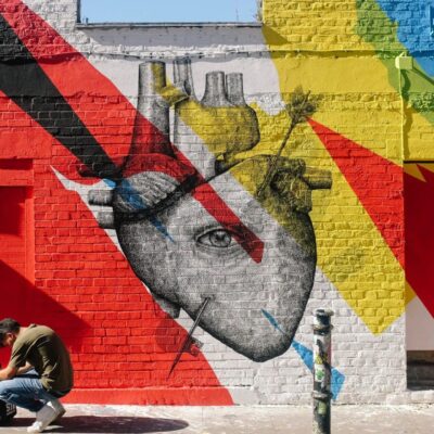 A man is painting a heart on the side of a building.