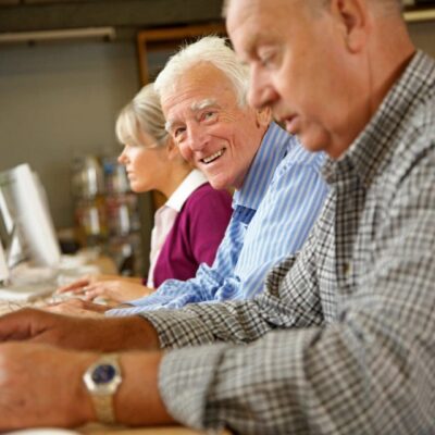 A group of older people using computers in a computer lab.