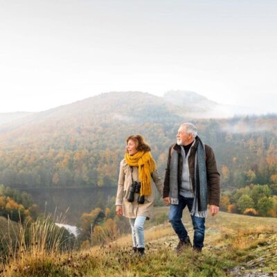A man and woman walking on top of a hill.