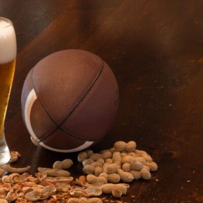 A glass of beer and peanuts on a table.