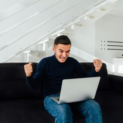 A man is sitting on a couch and using a laptop.