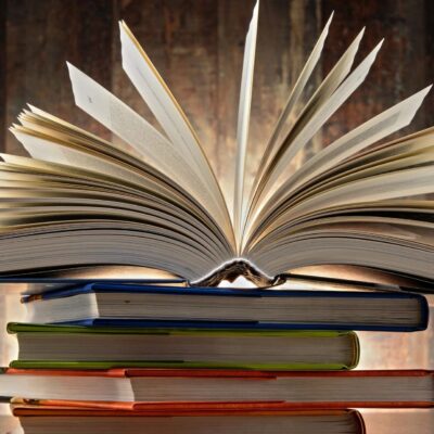 An open book on top of a stack of books.