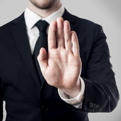 Man in suit holding hand up, stop gesture.