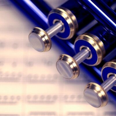 A blue trumpet sits on top of a sheet of music.