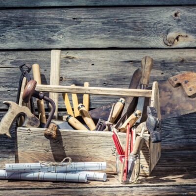 A wooden box full of tools on a wooden background.