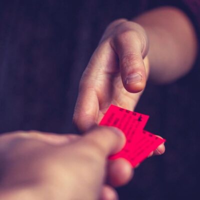 A person handing a red ticket to another person.