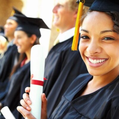 Smiling graduate holding diploma at ceremony.