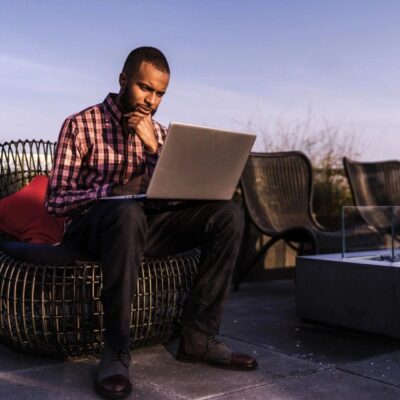 A man sitting on a chair using a laptop.